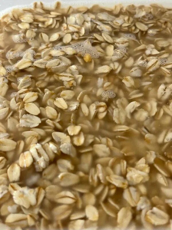 овес приготовление. отвар из овсяных хлопьев. геркулес залить кипятком. миска с крупой. геркулес в кипятке.