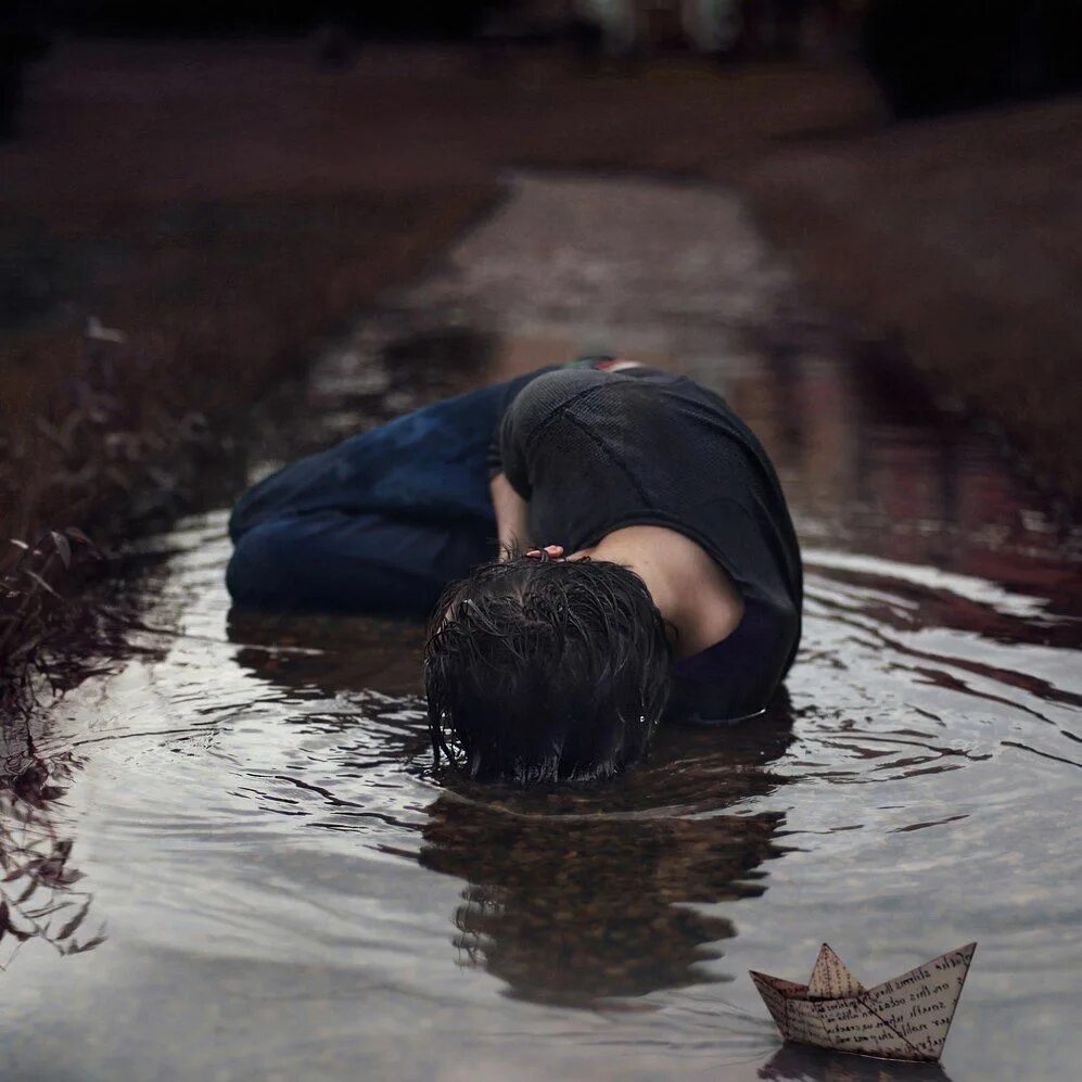 До слез очень грустный. Лежит под дождем. Человек лежит на земле под дождем. Грустный под дождем. Печаль.
