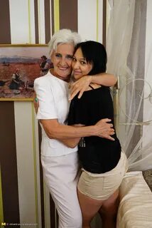 Naughty old and young lesbian couple making out on the bed.