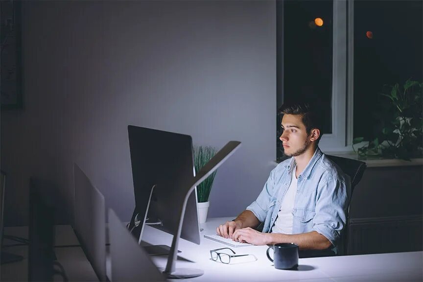Ночная подработка для мужчин. Человек за столом ночью. Человек сидит за компьютером. Молодой человек за компьютером в офисе. Человек сидит за компьютером ночью.