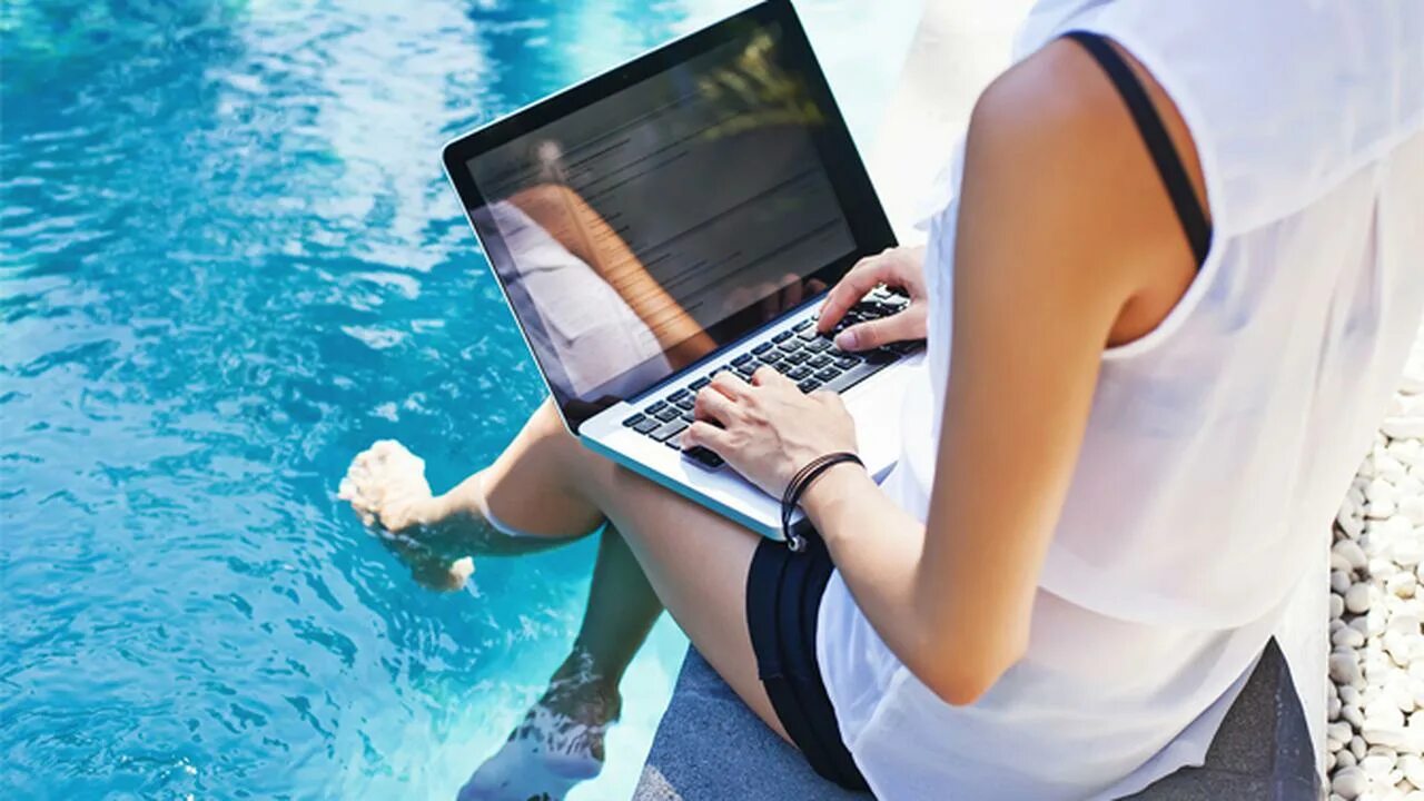 Удаленный фрилансер. С ноутбуком на пляже. С ноутбуком на море. Ноутбук на фоне моря. Девушка с ноутбуком на море.