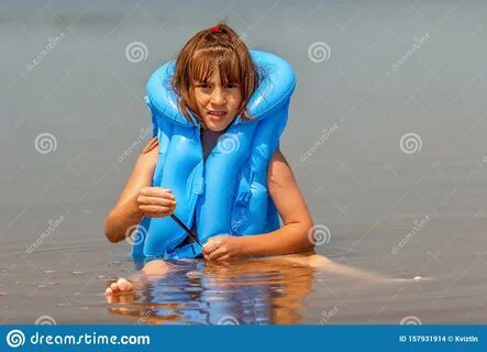 Child Girl In A Blue Inflatable Life Jacket Is Played In The Water With A B...