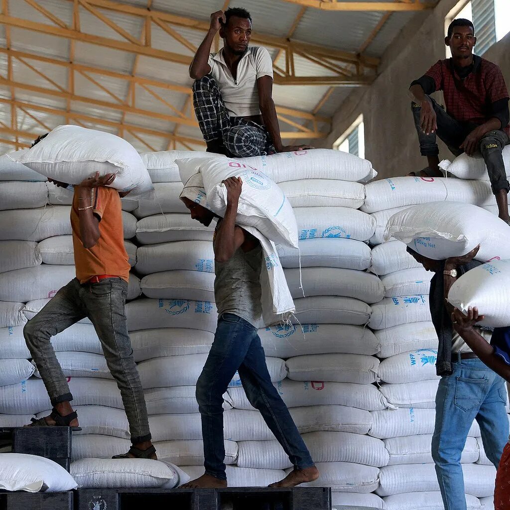 Мешок с зерном. Огромный циклон в Африке. Человек выгружает мешок на производстве. Зерно голод
