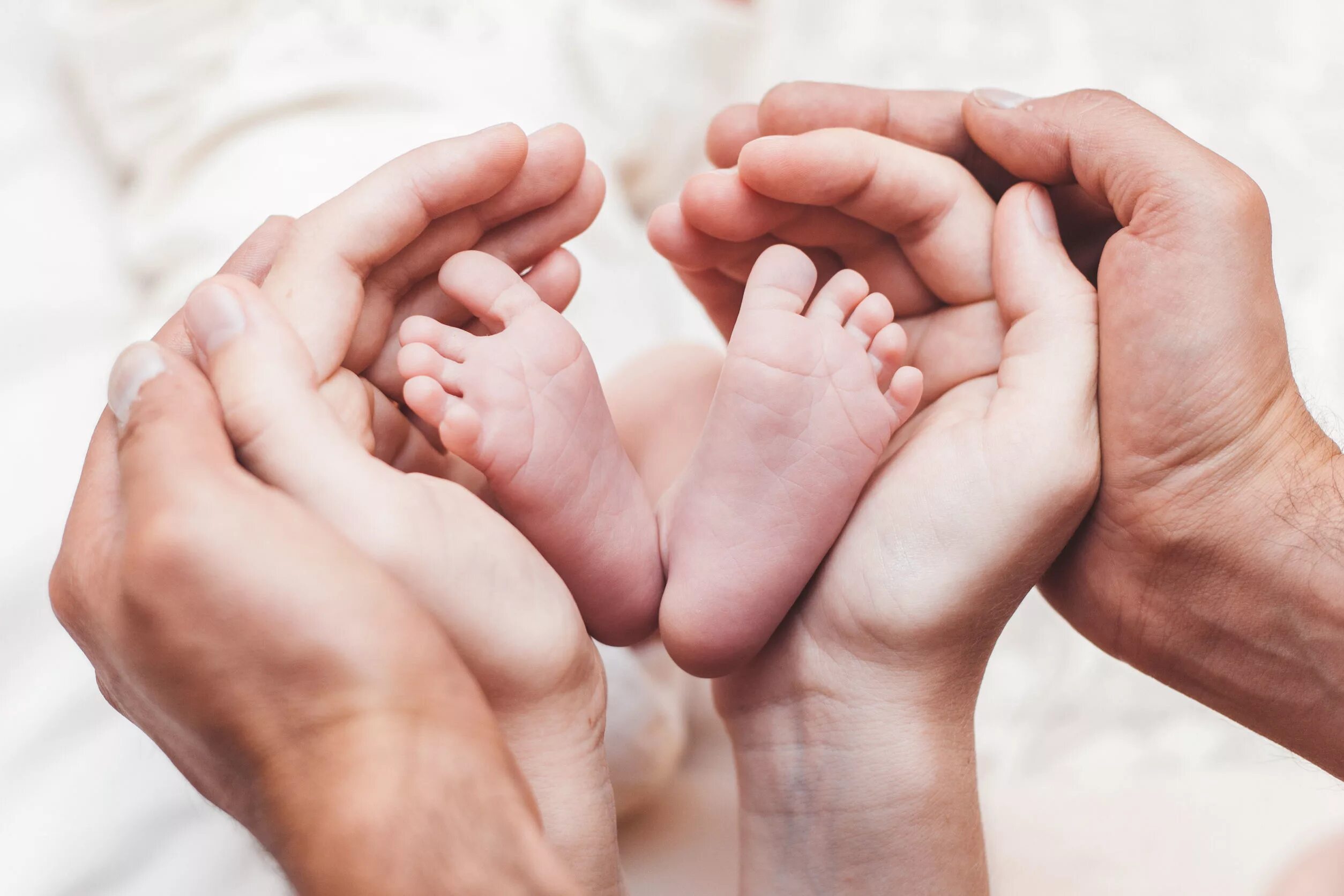 Мама передай папе. Мама с малышом на руках. Ножки малыша в руках. Ножки малыша в руках родителей. Пяточки младенца в руках.
