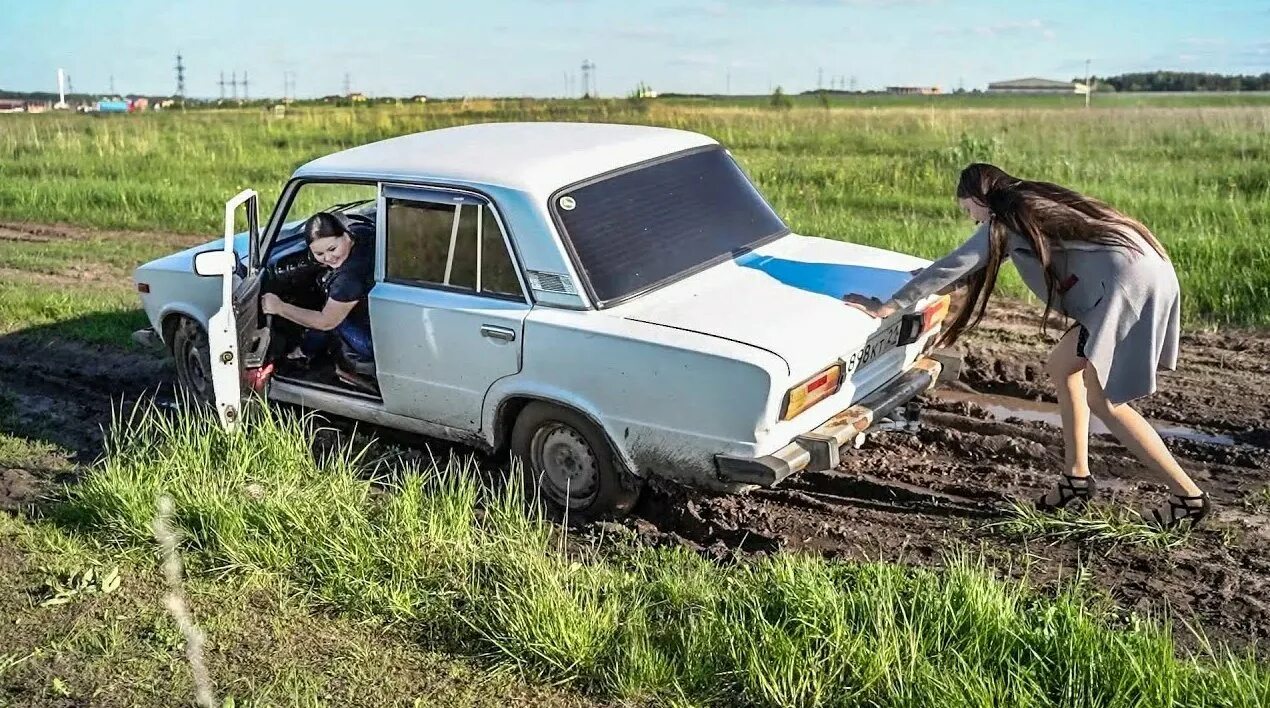 Машина забуксовала в грязи. Девушки и застрявшие автомобили. Толкают машину. Машина застряла. Глупая застряла