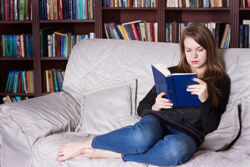 Девушка с книгой на диване. Человек на диване-книжке. Женщина сиит на диване с кнмжкой. Женщина сидит на диване с книжкой.