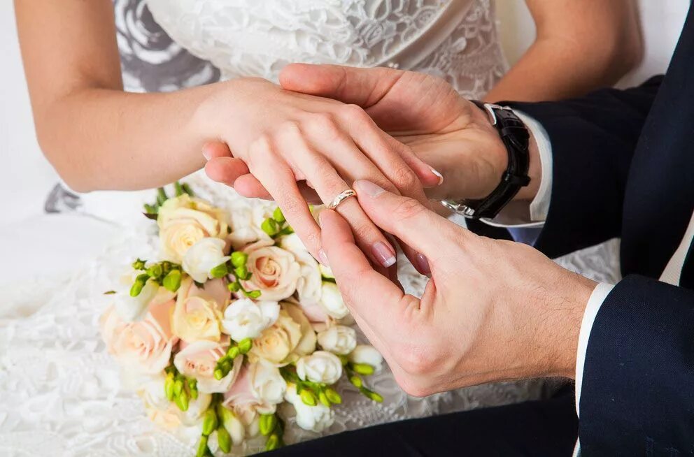 Свадебные кольца. Жених надевает кольцо невесте. Свадебные кольца на руках. Жених и невеста в загсе. Красивые жених и невеста.