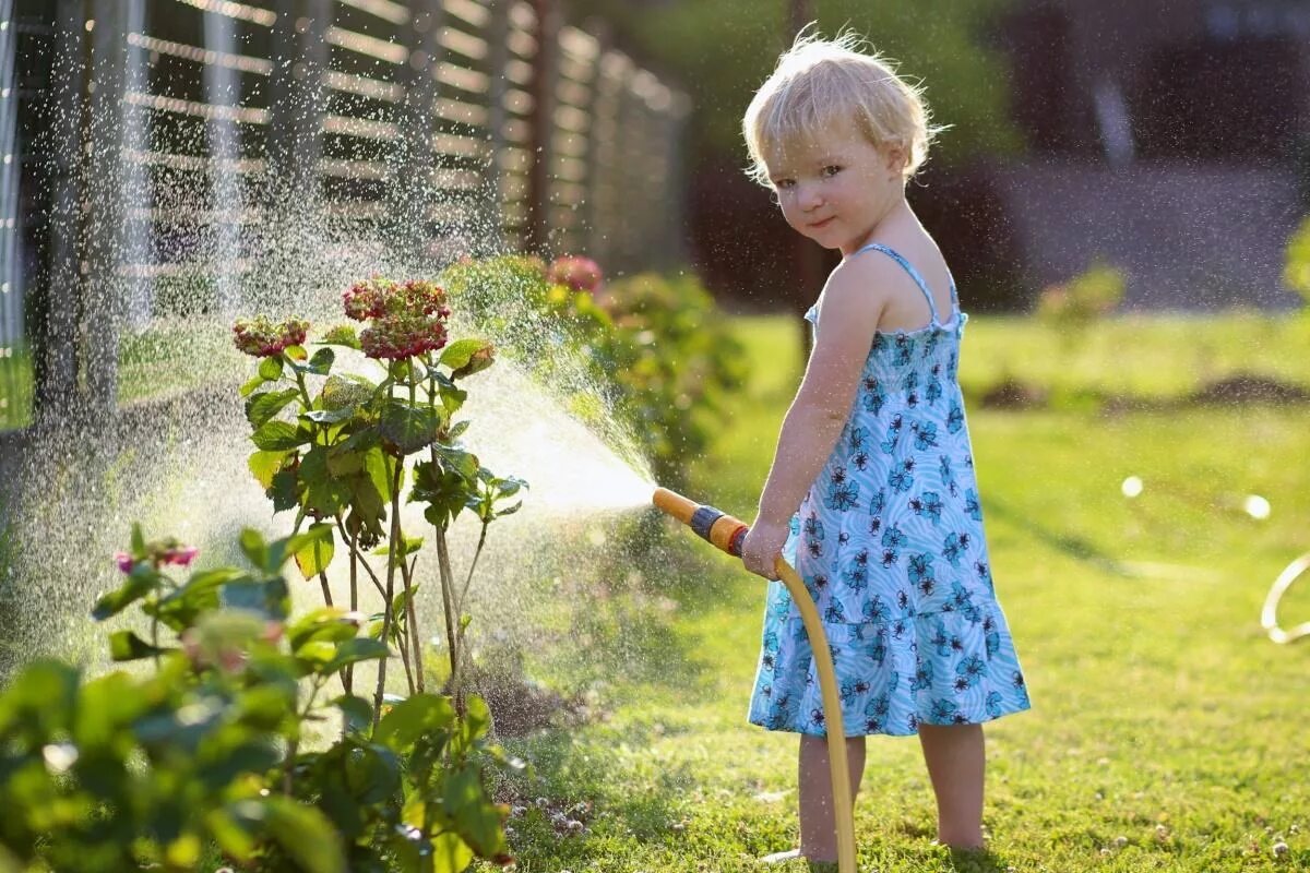 Девушка поливает цветы. Девочка поливает цветы. Девушка поливает цветы в саду. Девочка поливает цветы в огороде.