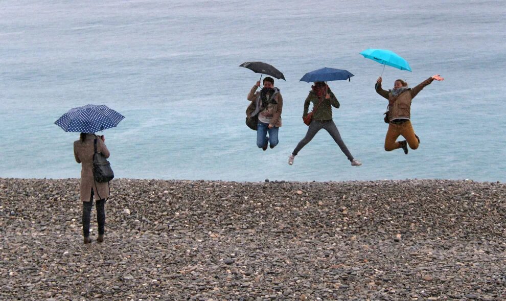 Rain beach. Дождь на пляже. Люди на пляже под зонтами. Турист под дождем. На пляже под дождем.