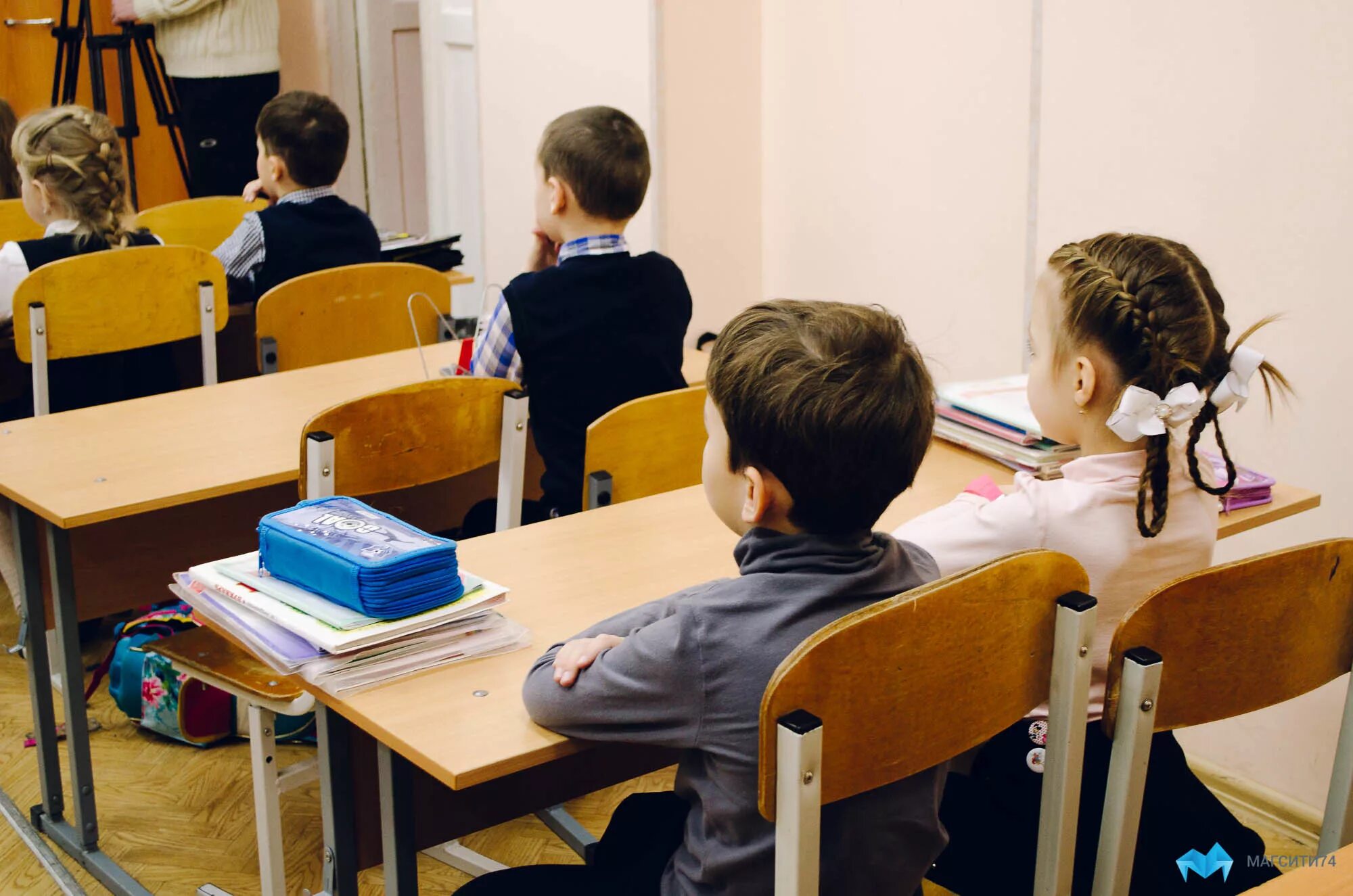 Старшеклассники в классе со спины. Школьник сидит за партой. Учитель и ученик. Занятия в школе. Уроки учителя.