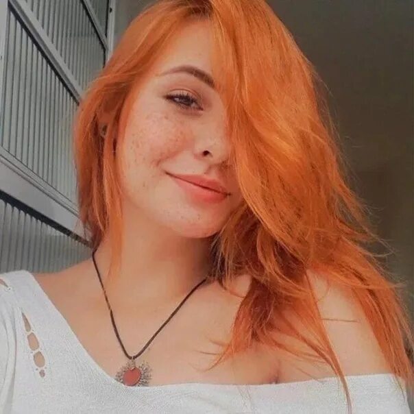 Рыженькая девушка в веснушках позирует на пляже