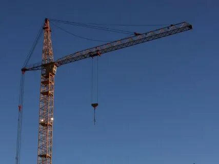 Башенный кран поднимает бетонную плиту массой