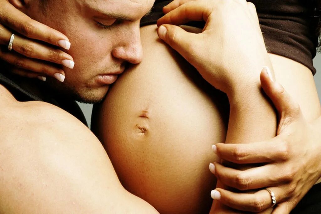 Обнимает беременную. Любовь беременной женщины. Мужчина целует живот беременной женщине.