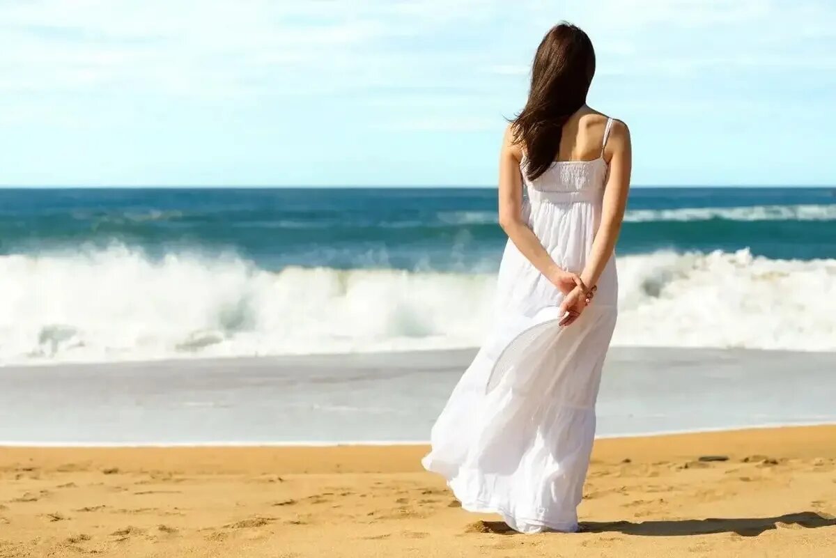 Девушка в длинном платье на море. Брюнетка на море. Девушка в длинном платье со спины. Девушка в белом платье на море. Женщина идет по берегу