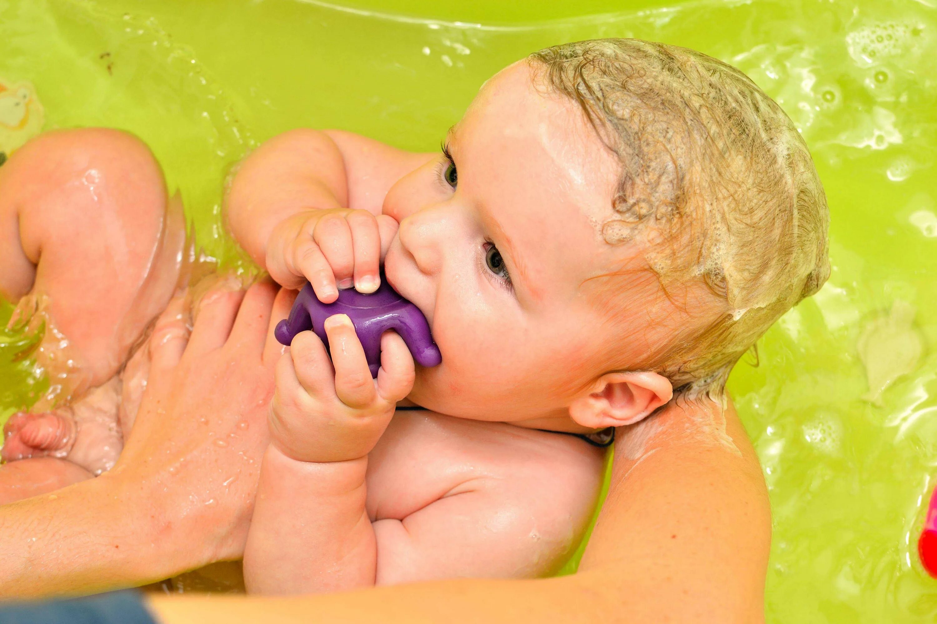 Мама измеряет температуру воды для купания ребенка. Пуканье новорожденного. Купание малыша. Мытье ребенка. Для купания новорожденных приспособления.