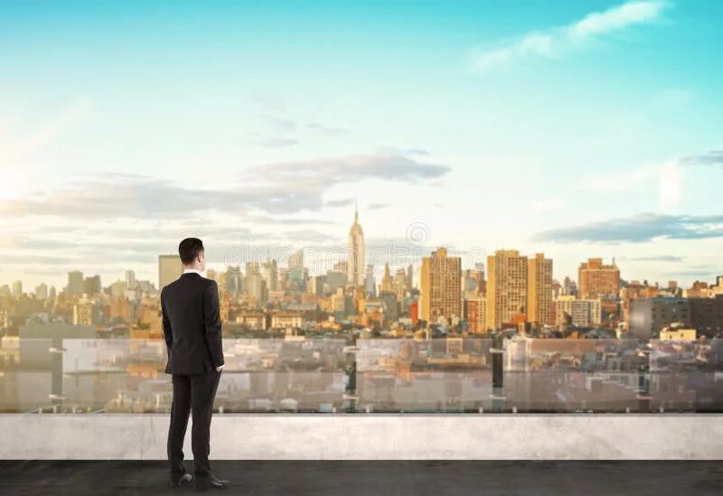 Look at building a that. Парень смотрит на город. city with low buildings, people, cars, 2 men standing on the right, talking.