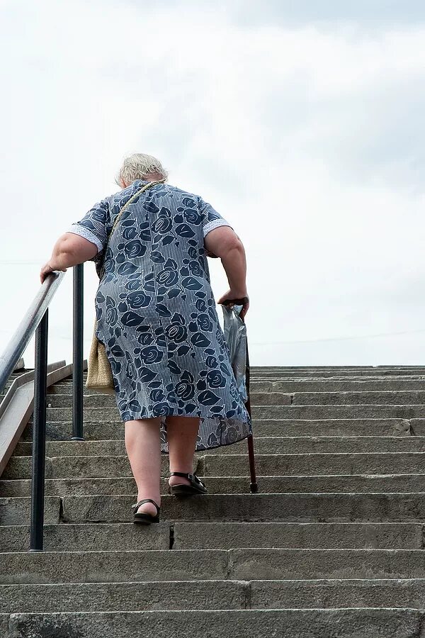 Дамы потихоньку пошли за поднимавшимся по лестнице. Бабушка по ступенькам. Бабушка идет АО летчнице. Пожилая женщина идет. Бабки на лестнице.