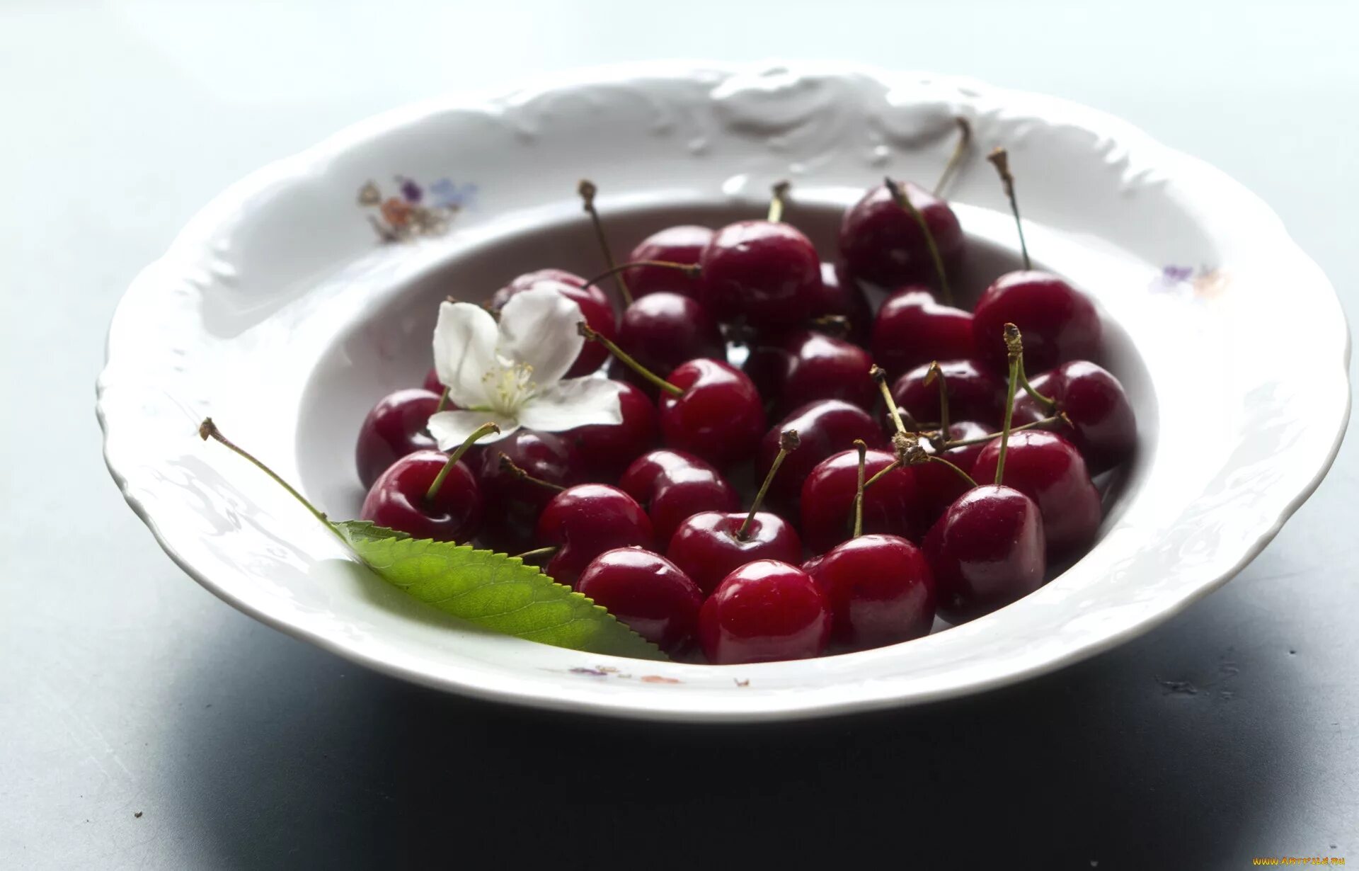 На тарелке лежат вишни. Черешня в тарелке. Вишня на белом фоне. На тарелке лежат одинаковые на вид пирожки. На тарелке лежат вишни.