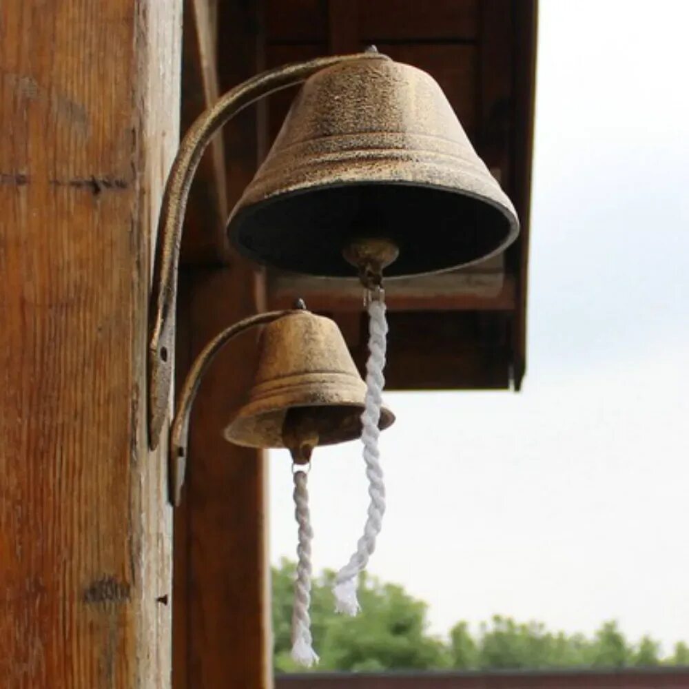 Висит колокольчик. Крепление для колокола на стену кованное. Колокол с веревкой можно подсоединить к дверному звонку.