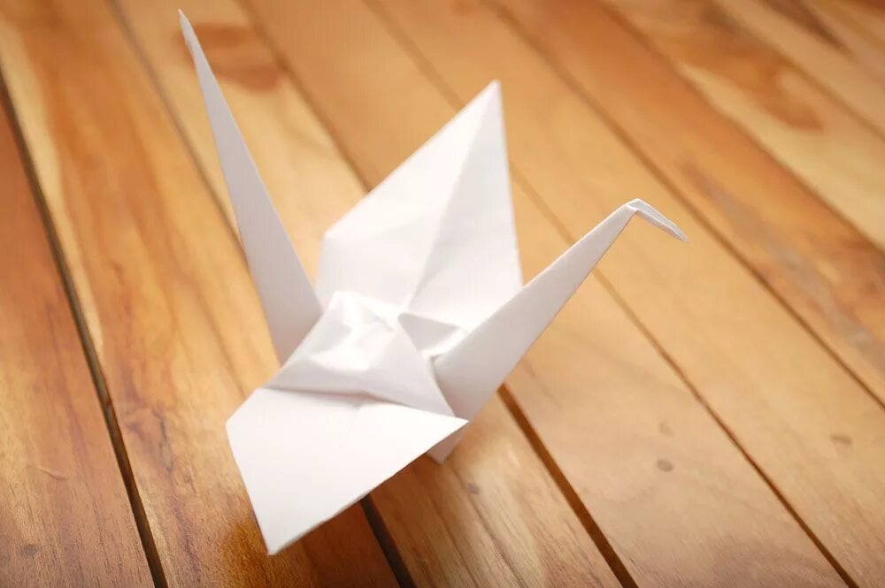 Бумажный журавль. Журавлик из бумаги. Журавль оригами. Бумажный журавль оригами. Журавлик на столе.