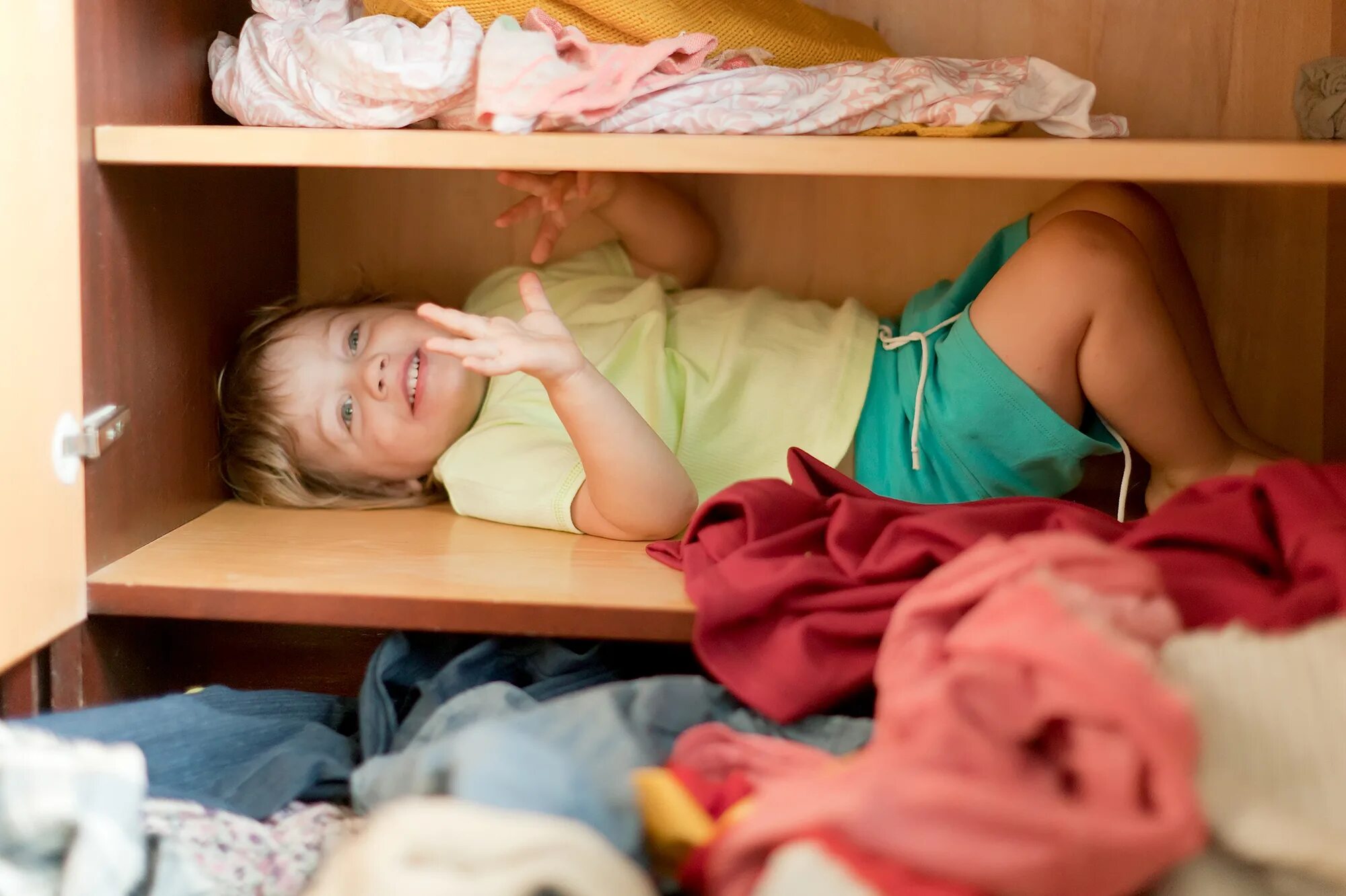 Складываем одежду девочки в шкаф. Девушка прячется в шкафу. Ребенок складывает вещи в шкаф. Спрятался в шкафу. Девочка спит в шкафу.