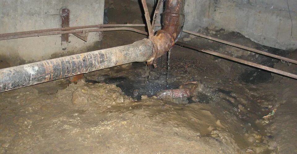 Течь в подвале многоквартирного дома. Канализационные трубы в подвале. чугунная канализация в подвале. трубопроводы в подвале. канализация в подвале многоквартирного дома.