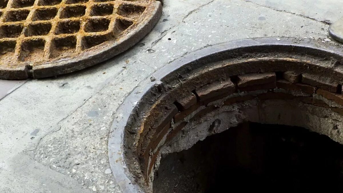 открытый люк на дороге. крышка для костровой чаши 80 см. неровная крышка. асфальт на крышку люка канализационного. канализационный люк в асфальте.