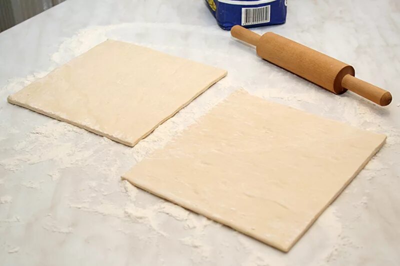 скалка для раскатки теста. приготовление слоеного теста. пласт дрожжевого теста. меньше теста. раскатка дрожжевого слоеного теста.