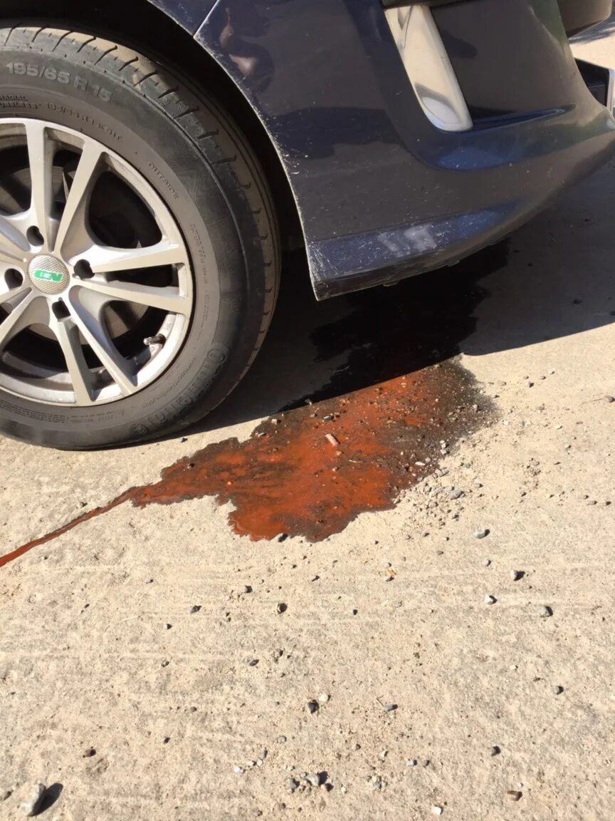 Оранжевая жидкость под машиной. Из машины капает масло