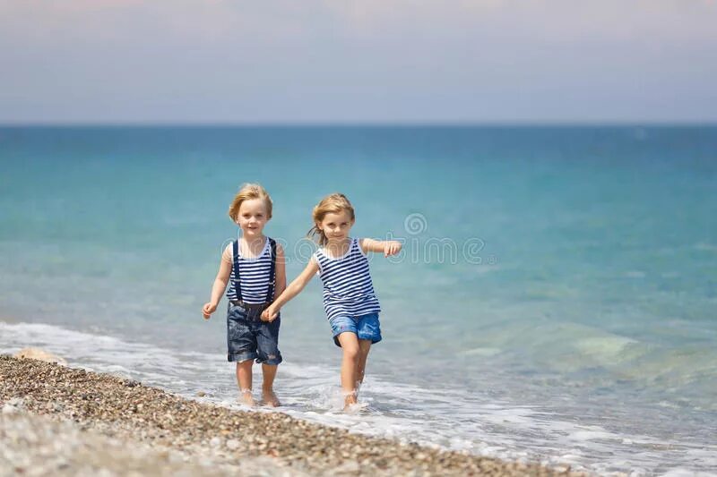 Дети гулять по пляжу. Дети гуляют с родителями на берегу моря. Фото на море идет с сестрой.