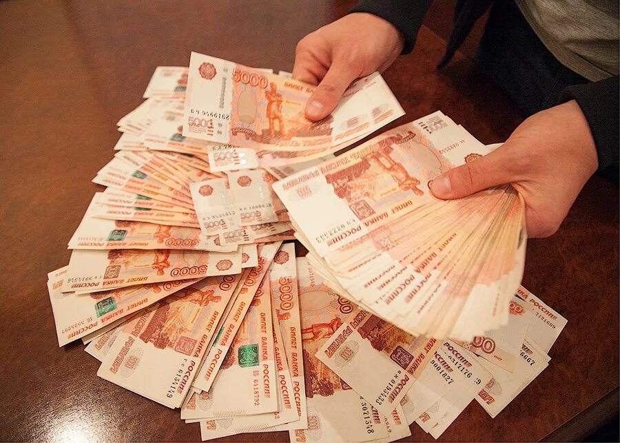 5 000 рублей в суммах. Деньги в руках. пятитысячные купюры на столе. миллион рублей. большие деньги.