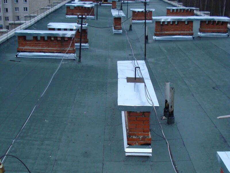 трубы на крышах многоквартирных домов. вентиляционные трубы на плоской крыше. вытяжная система на плоской кровле. трубы на крышах многоэтажных домов. молниезащита вентиляционной шахты на кровле.
