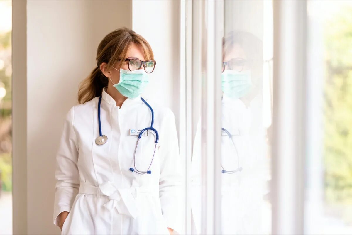 Женщина врач стоит. Девушка врач стоящий у окна. Врач эмоции. Портреты женщин врачей фото.