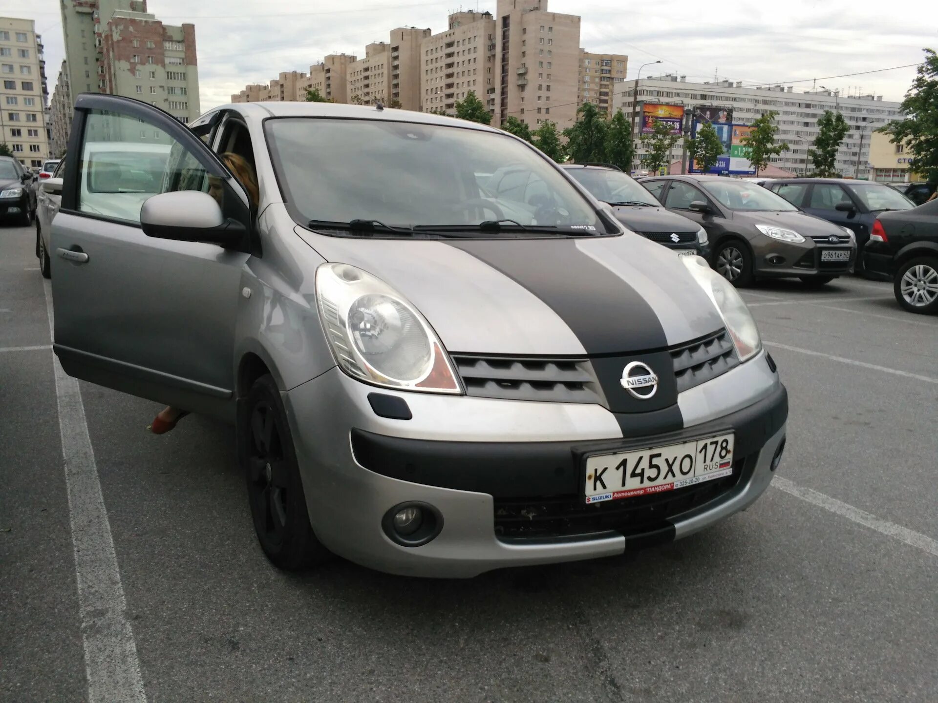 Марка машины Nissan Note. Enot машина. Авто енот Ниссан. Енот в машину Ниссан ноут.