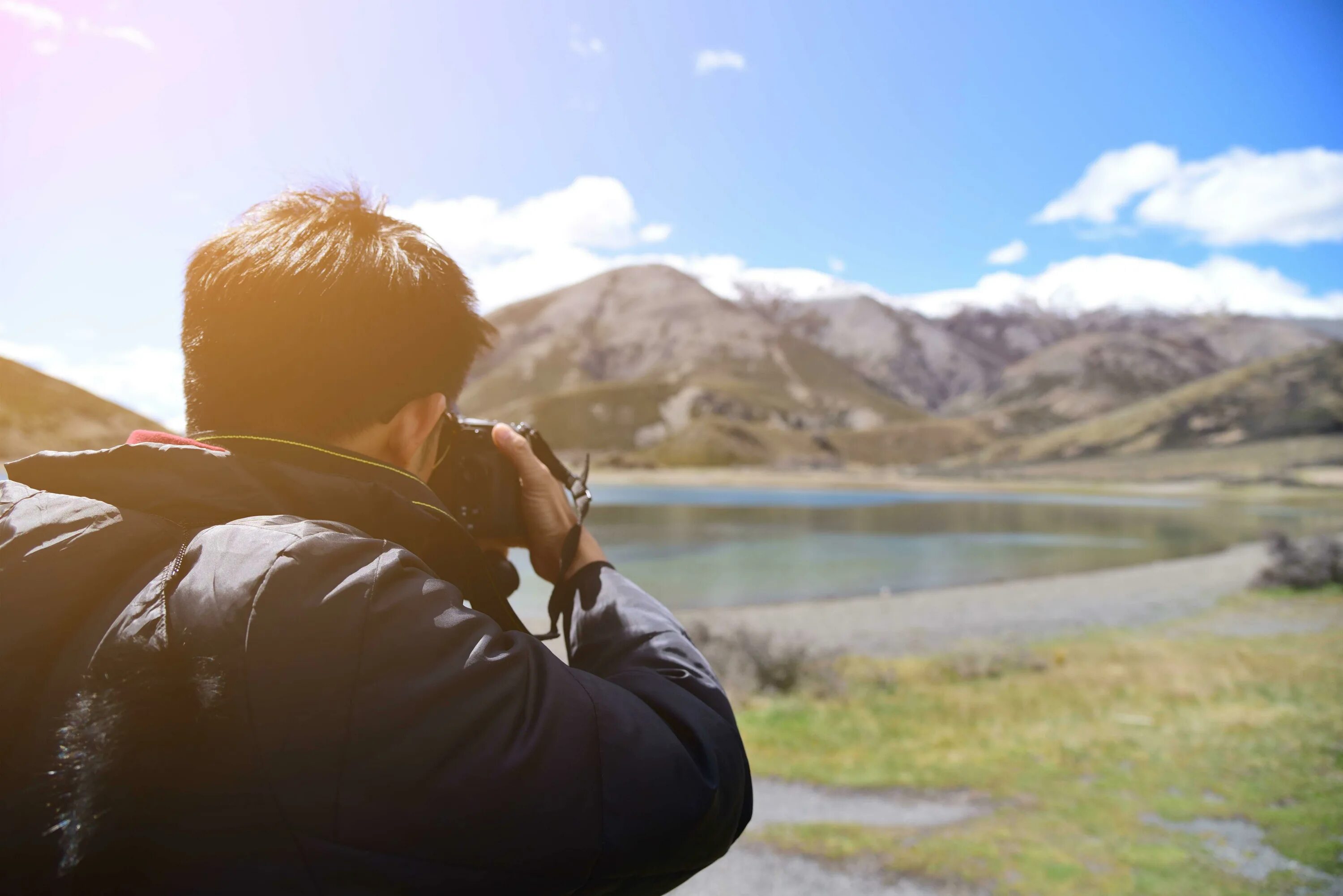 Фотограф на фоне гор. Человек фотографирует горы. Фотографирование в горах. Человек с фотоаппаратом в горах.