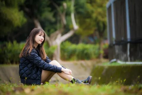 Wallpaper Asian girl in a black jacket sits on the grass.