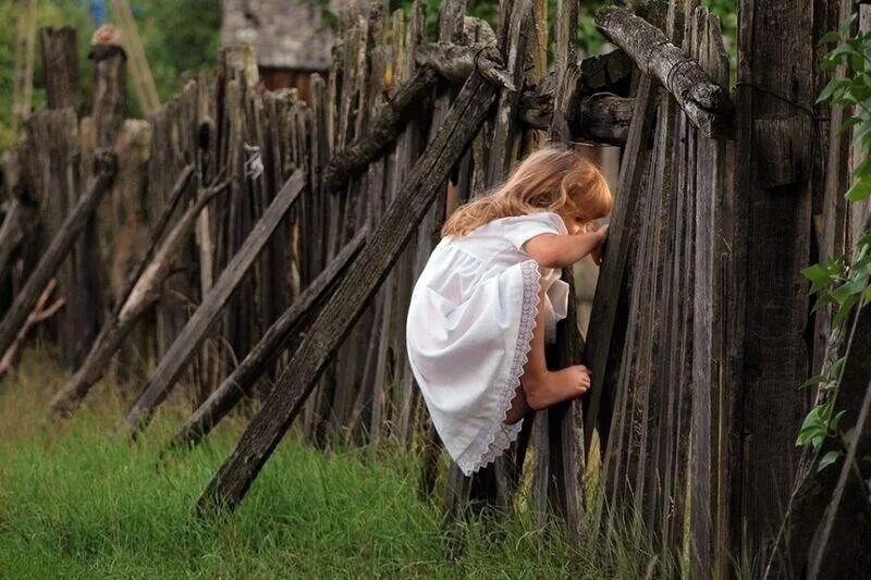 Вновь заглядывать. Заглядывает за забор. Фотосессия у забора. Девочка на заборе.