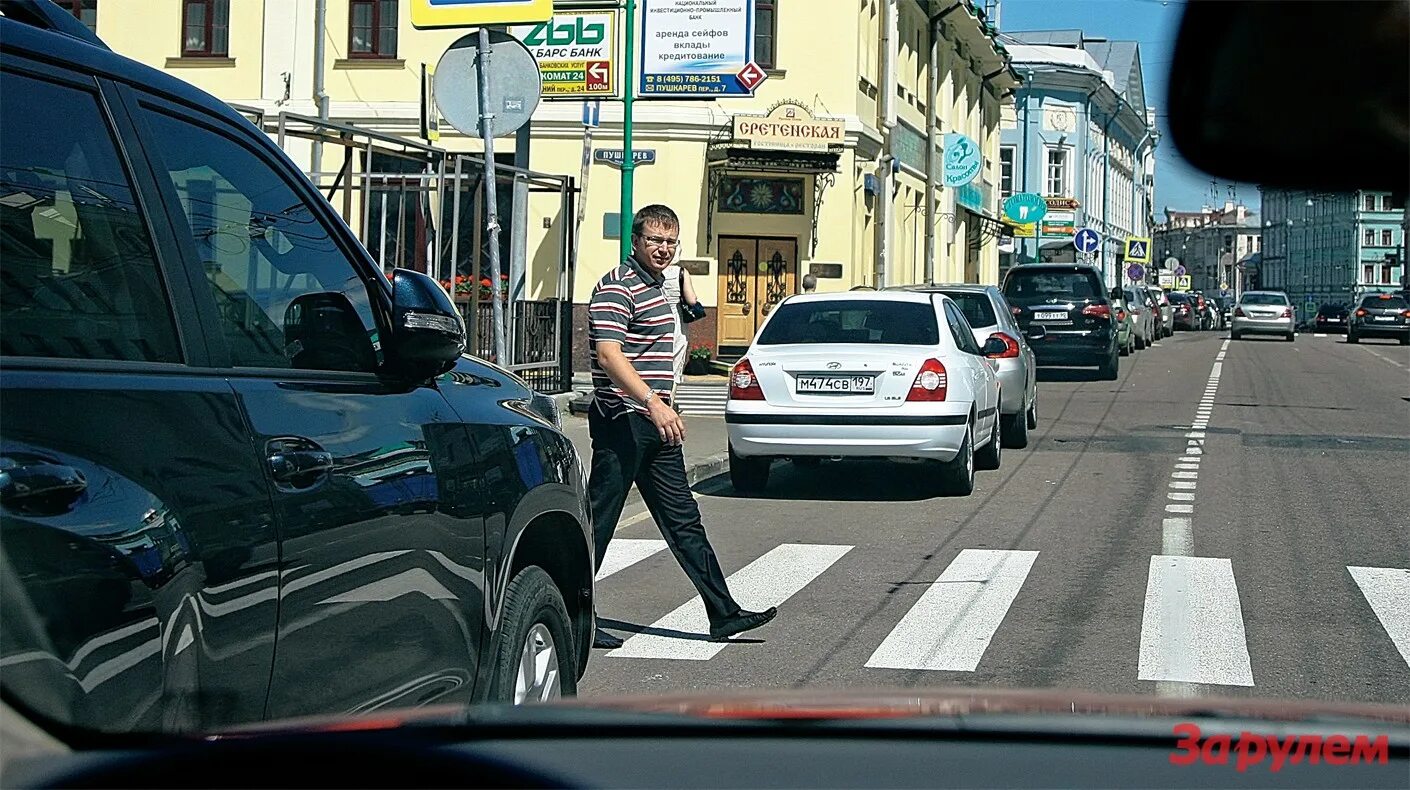 Человек остановился возле одноэтажного. Пешеход. Машины пропускают пешеходов. Водитель пропускает пешехода. Машина не пешеходном переходе.