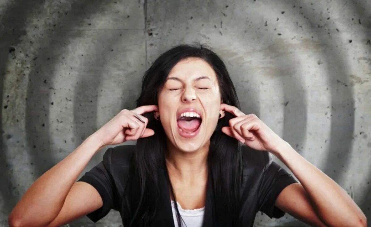 Раздражительность человека. Зажатая женщина. Неприятный звук. Раздражающий звук. Девушка закрывает уши.