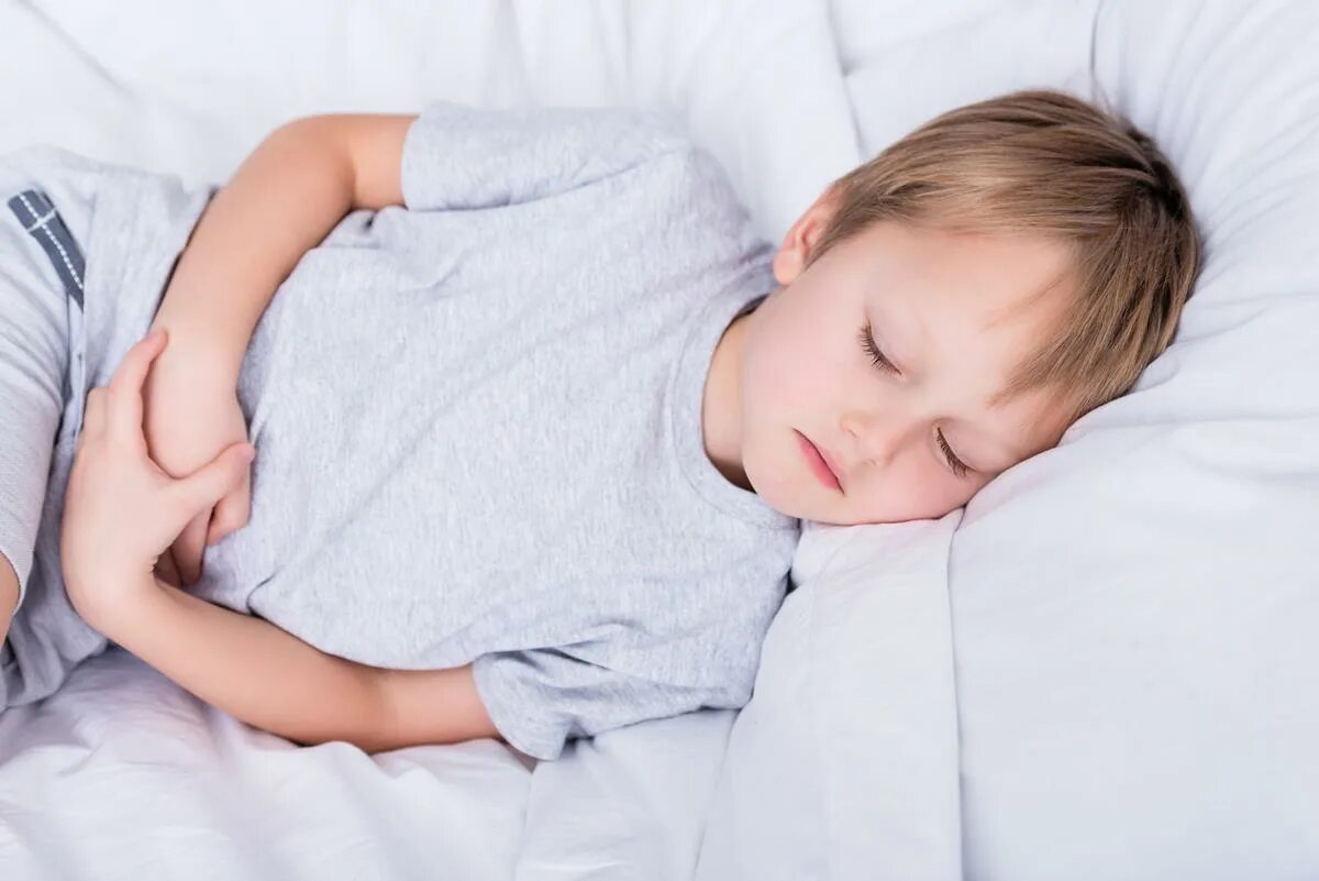Мальчик лежит на кровати. Мальчик лежит на мальчике на кровати. Картинки мальчик лежит в кровати. Мальчик лежит на животе. Симптомы боли в животе у ребенка