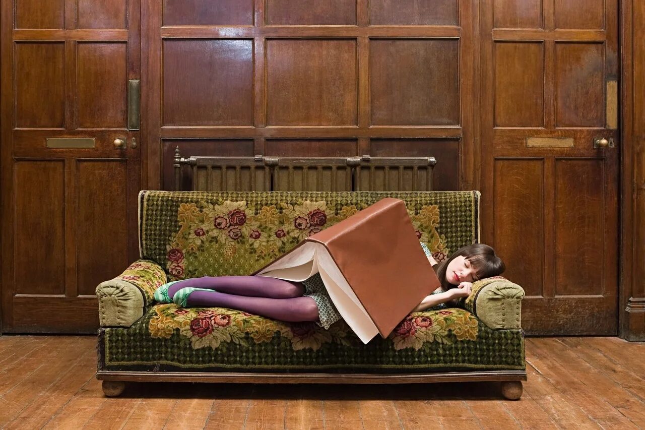 Книга лежит в шкафу. Девушка с книгой на диване. Диван книжка для девочки. Диван книга. Девушка лежит на диване с книгой.