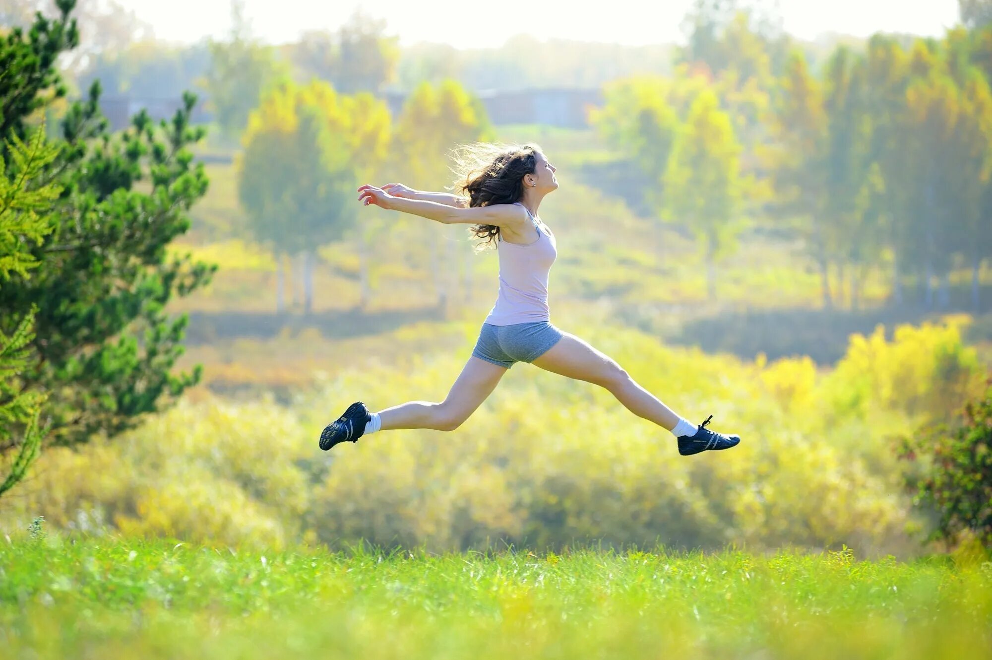 Девочка прыгает на пляже. Девушка прыгает. Молодая девушка прыгает. Девушка прыгает в поле. Спортивная девушка счастливая прыгает.