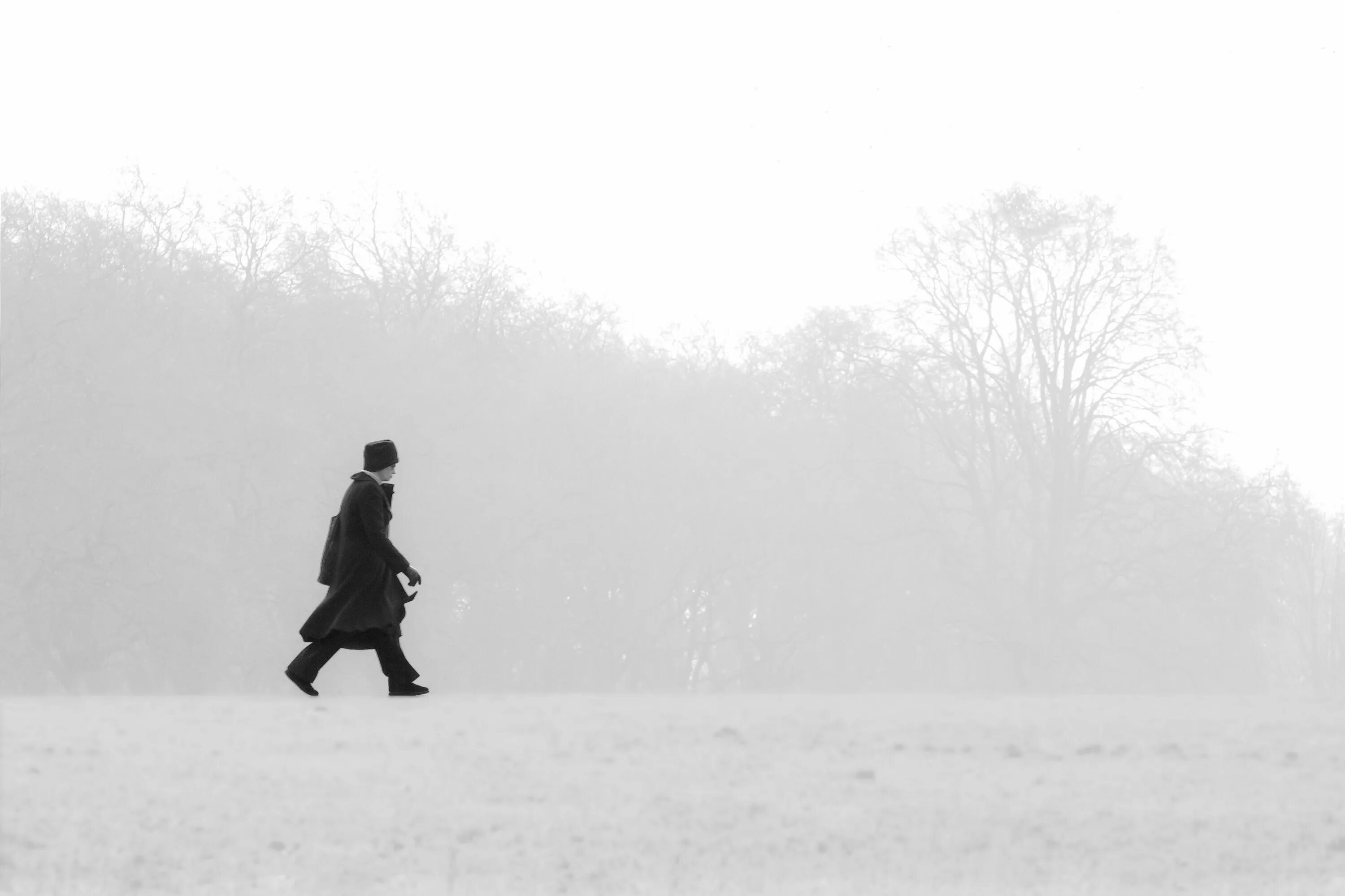 Одинокий человек в снегу. Мужчина идет. Одинокий человек зимой. Силуэт путника. И надрываясь в метелях