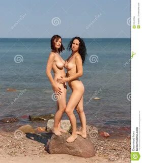 Dos mujeres desnudas jovenes que toman el sol en la playa.