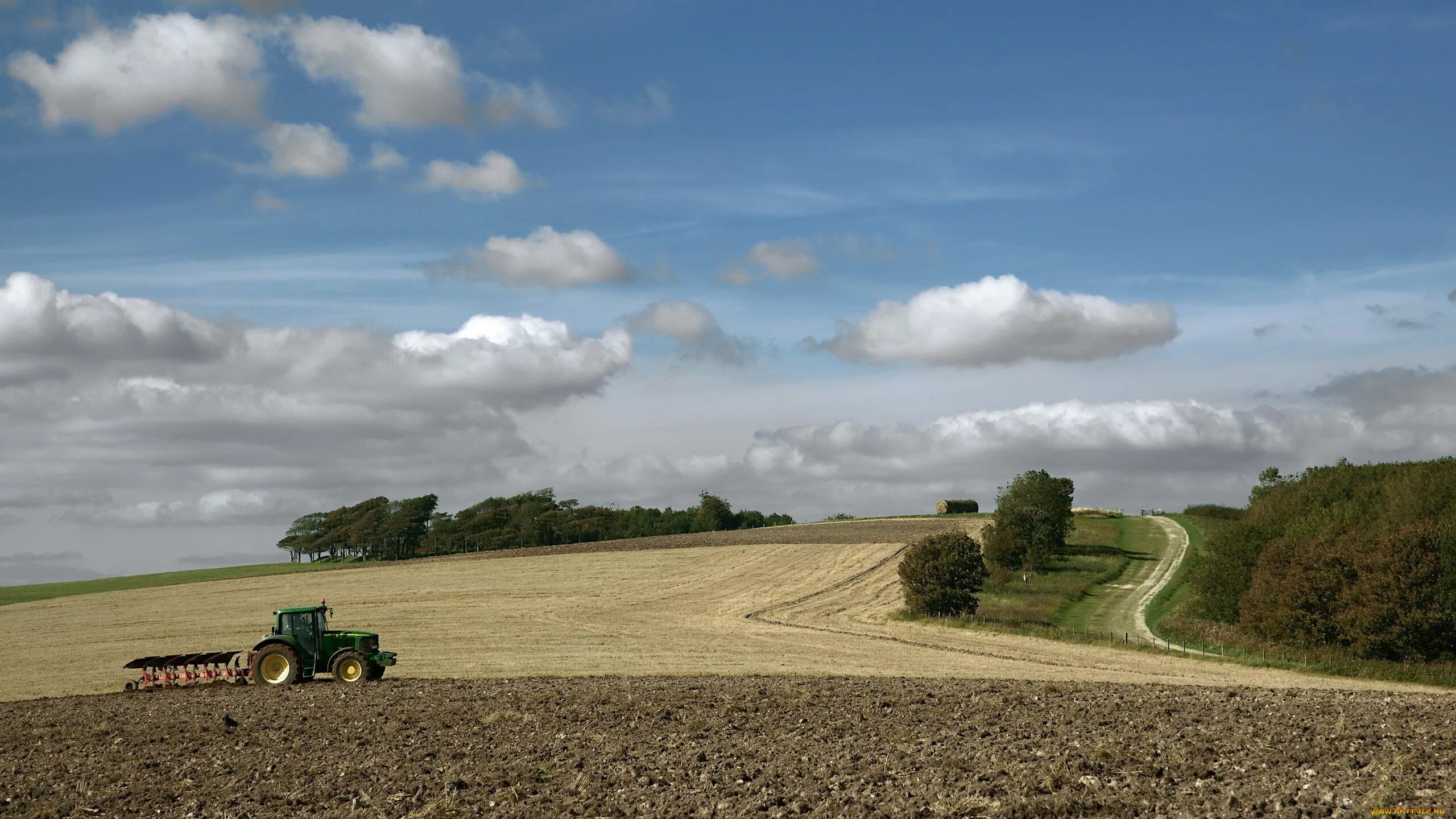 Вдалеке трактор пашет поле Иноковка. Пахотные поля Белоруссия. Трактор в поле. Поле деревня.