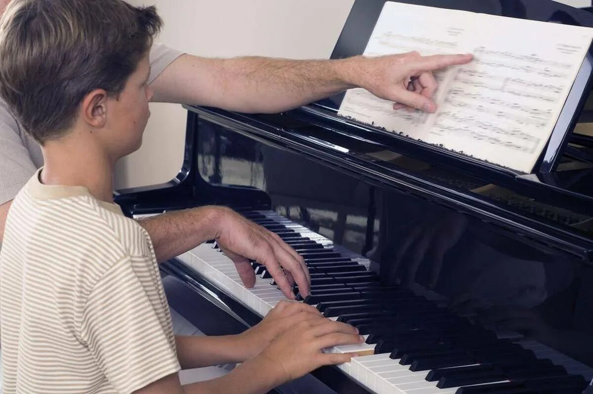 Учат играть пианино. Занятия на фортепиано. Уроки пианино. Уроки фортепиано. Человек за пианино.
