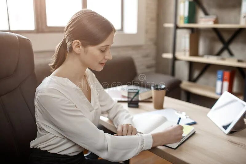 She is sitting at the table. Женщина сидит за столом сбоку. Девушка за столом сбоку. Девочка за столом боком. Девушка сидит за столом сбоку.