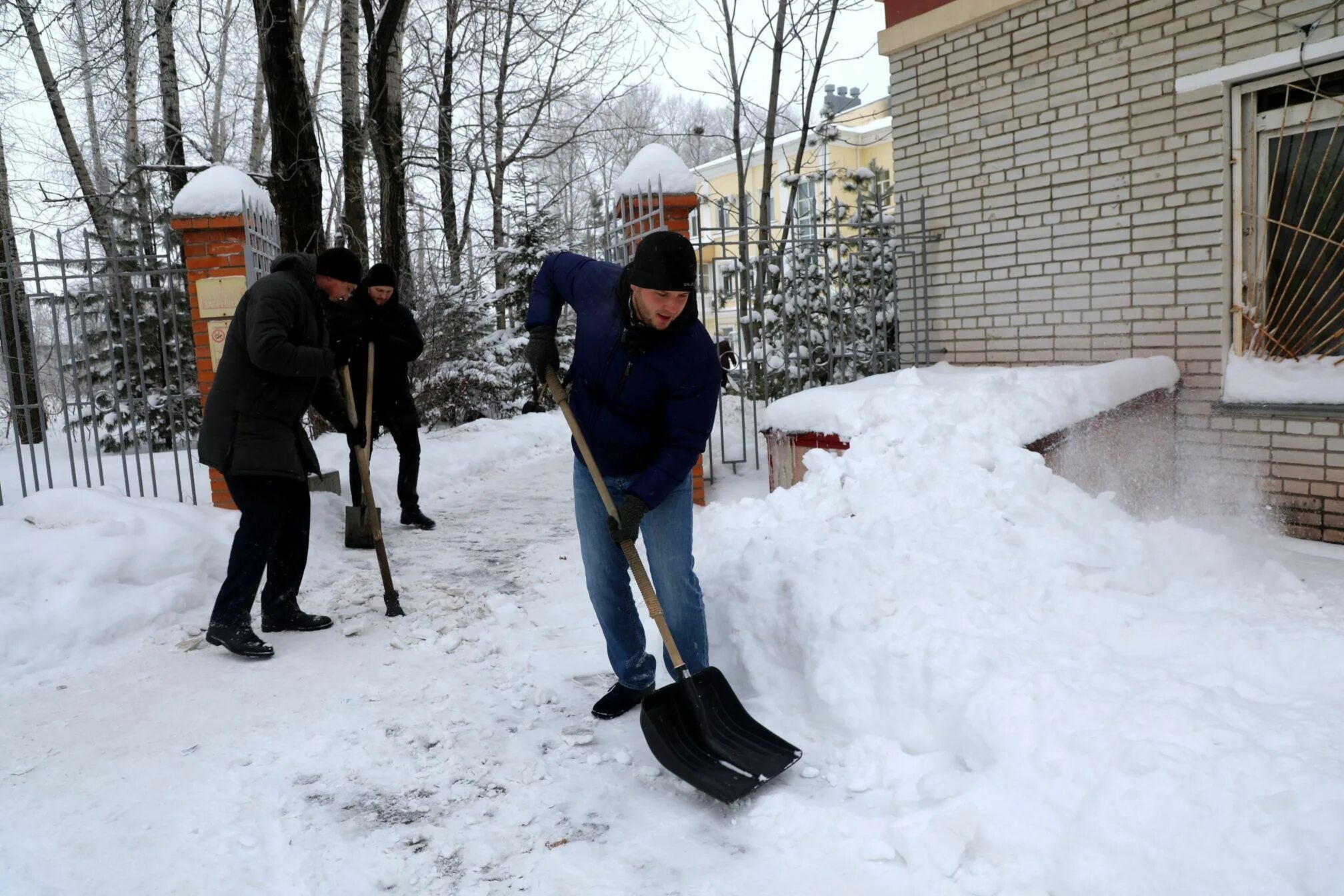 Человек убирает снег. Чистка снега во дворе. Убиратель снега. Убирает снег лопатой. Человек убирает снег.