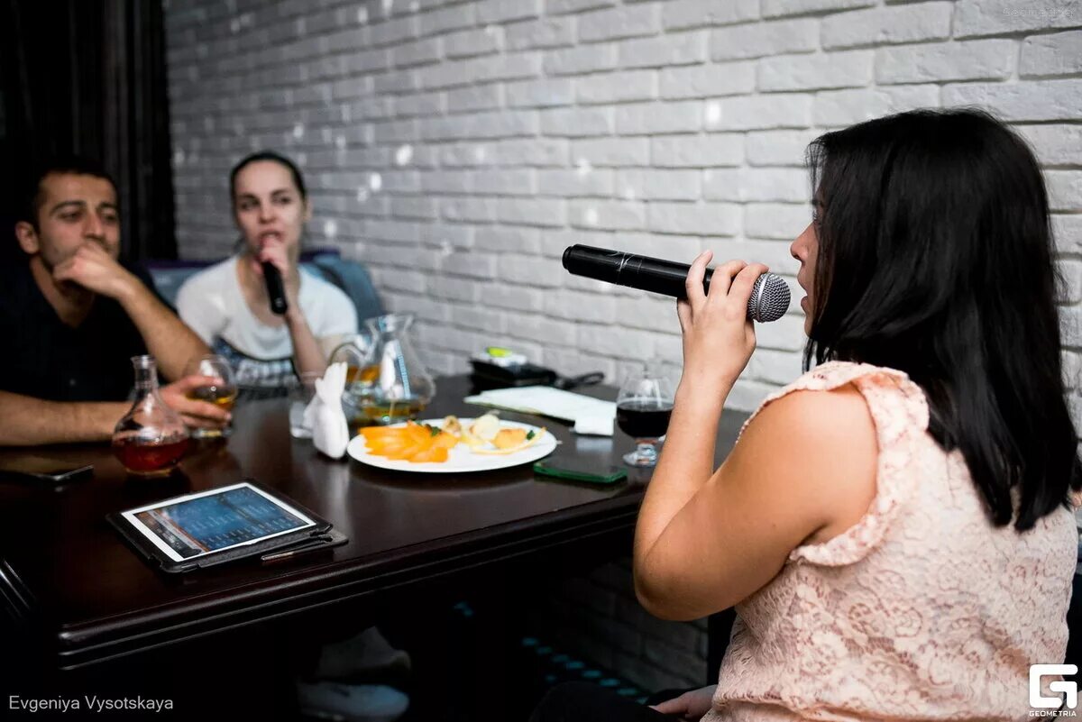 Караоке. Девушка поет в баре. Поют за столом. Поют караоке в баре.