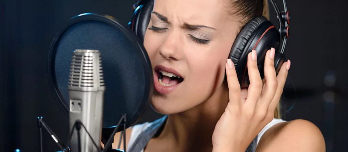 Вокальная постановка. Вокал. Человек поет в студии. Девушка перед микрофоном. Певица в студии звукозаписи.